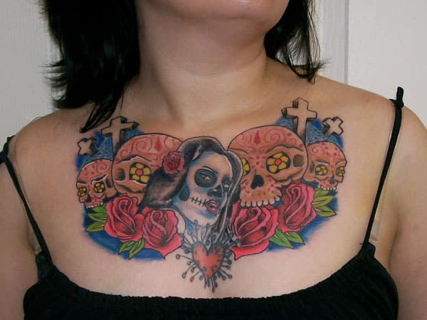 Tatuaje mujer en claviculas, calaveras y Santa Muerte